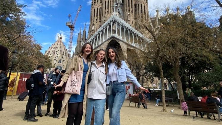three female students standing together at a landmark